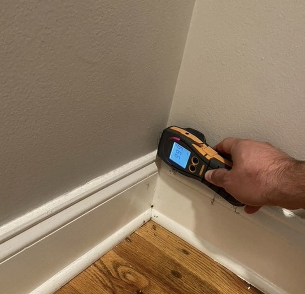 Columbus Water Damage technician using a moisture meter to map hidden water along a baseboard